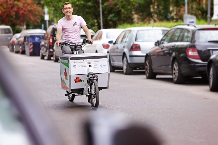 Ein junger Mann fährt entspannt auf einem Longjohn-Lastenrad